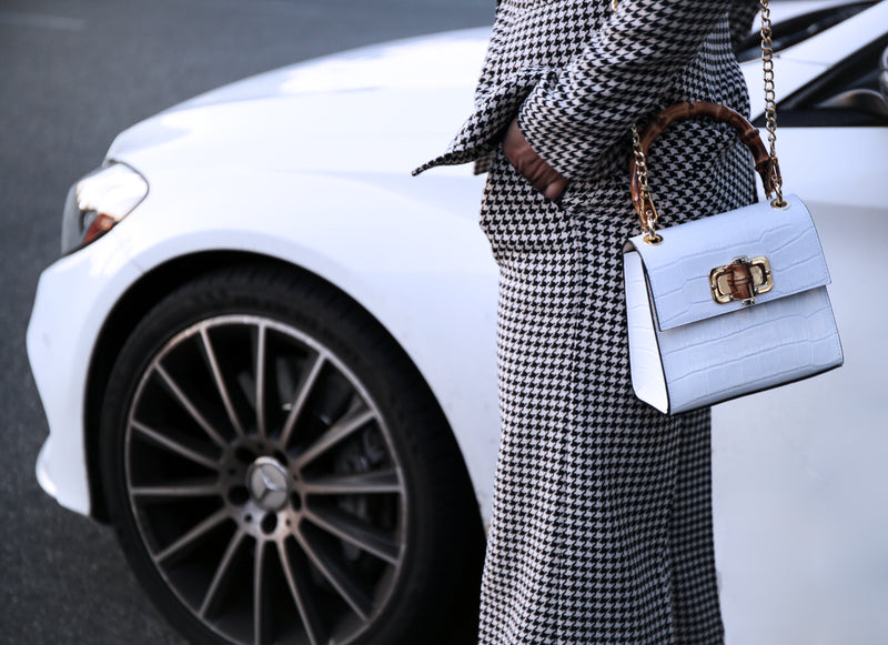 Lower half of girl in houndstooth suit, Gaia Handbag Blanco in front of white Mercedes- Benz C43   